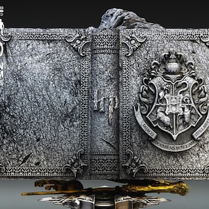 May include: A detailed, gray resin sculpture of an open book with the Hogwarts crest on the right side. The book has intricate detailing and the text "Hp" on the spine. A golden wand rests below the book.