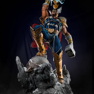 Puede incluir: Estatua detallada de un superhéroe en una pose dinámica, sosteniendo un martillo brillante en alto. La figura lleva un traje azul y dorado con una capa roja, de pie sobre una base rocosa. La estatua es muy detallada con un fondo oscuro.