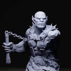 May include: A gray bust of a muscular, bald humanoid figure with pointed ears and a stern expression. The figure wears spiked armor and holds a chain weapon. The sculpture has a detailed, textured surface.