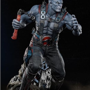 May include: A detailed statue of a muscular, blue-skinned humanoid figure. The figure wears a black and gray outfit with red and blue accents, a belt buckle with a red emblem, and spiked shoulder pads. It holds a red weapon with a chain.
