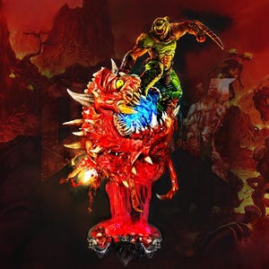 May include: A detailed figurine depicting a character from the video game Doom, standing atop a monstrous, red demon. The demon has sharp teeth and horns, with a blue and green energy effect. The background shows a fiery landscape.