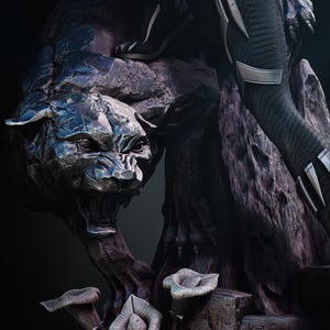 Può includere: Scultura dettagliata di una creatura simile a una pantera con un'espressione feroce, posta su una base rocciosa con flora stilizzata. La scultura ha una lucentezza metallica, con toni scuri e dettagli intricati. Una figura in abito nero è in piedi sulla scultura.
