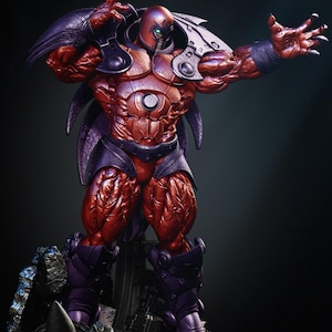 May include: A detailed figurine of a muscular, red-skinned character with purple armor and a helmet. The figure is posed with one arm outstretched, showcasing intricate detailing and a dynamic stance. The figure stands on a rocky base.