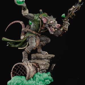 May include: A detailed figurine of a rat-like creature in a green coat, holding a glowing green orb and a crossbow. The figure stands on a stone base with a sewer pipe and green, bubbly substance. The rat has glasses and a menacing grin.