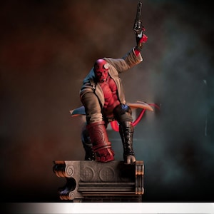 Puede incluir: Una figura musculosa de piel roja con cuernos, que lleva un abrigo y botas color beige, sosteniendo una pistola. La figura posa sobre una estructura de piedra, con una cola roja visible. La estatua es una representación detallada de un personaje de cómic.