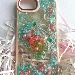 Cover per telefono in resina con motivo floreale 3D, realizzata a mano, con fiori rosa pastello e foglie pressate.