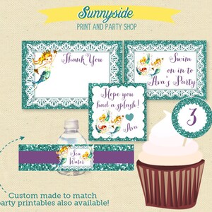 Op de afbeelding: Een set bedrukte feestversieringen met een zeemeermin-thema. De versieringen omvatten een bedankkaart, een bord met de tekst "Swim on in to Ava's Party", een cupcaketopper met het nummer 3 en een waterfleslabel met de tekst "Sea Water".