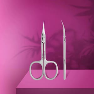 Könnte beinhalten: Silberne Nagelscheren mit gebogenen Klingen und Fingerlöchern, präsentiert auf einer rosa Oberfläche vor einem rosa Hintergrund. Der Text "STALEKS PRO EXPERT 80/2" ist auf die Schere gedruckt.