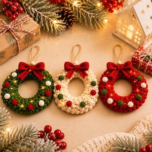 May include: Three circular crochet wreaths with hanging loops, each featuring a red yarn bow at the top. The wreaths are green, cream, and red, decorated with small contrasting yarn pom-poms and integrated warm white fairy lights.