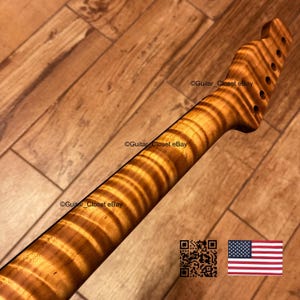May include: A guitar neck made of light brown wood with a prominent tiger stripe flame maple grain pattern. The headstock features six circular tuning peg holes arranged in a single row. The text Guitar_Closet eBay appears on the image.