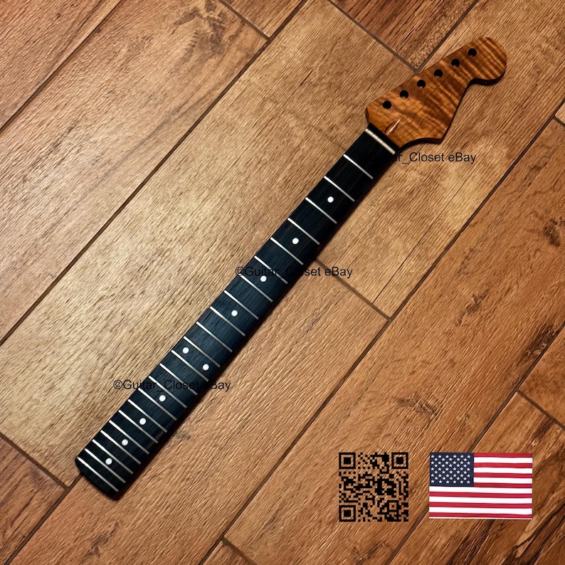 Może przedstawiać: Gryf gitarowy z ciemną, gładką podstrunnicą z białymi okrągłymi znacznikami pozycji oraz jasnobrązową gł&oacute;wką o wzorze tygrysich pas&oacute;w. Gł&oacute;wka posiada sześć nawierconych otwor&oacute;w na klucze stroikowe oraz widoczną strukturę drewna.