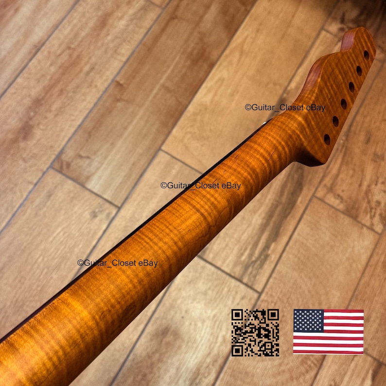 May include: A guitar neck with a flamed maple finish. The neck has a natural wood color with a prominent grain pattern. The headstock features six tuning peg holes. The image also includes a QR code and the American flag.