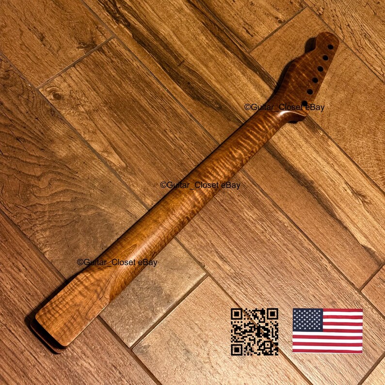 K&ouml;nnte beinhalten: Ein Gitarrenhals aus gemasertem Holz mit einem ausgepr&auml;gten Riegelahorn-Muster. Die Kopfplatte verf&uuml;gt &uuml;ber sechs vorgebohrte L&ouml;cher f&uuml;r die Stimmmechaniken in einer Reihe. Das Holz hat ein warmes, mittelbraunes Finish mit nat&uuml;rlichen Maserungen.