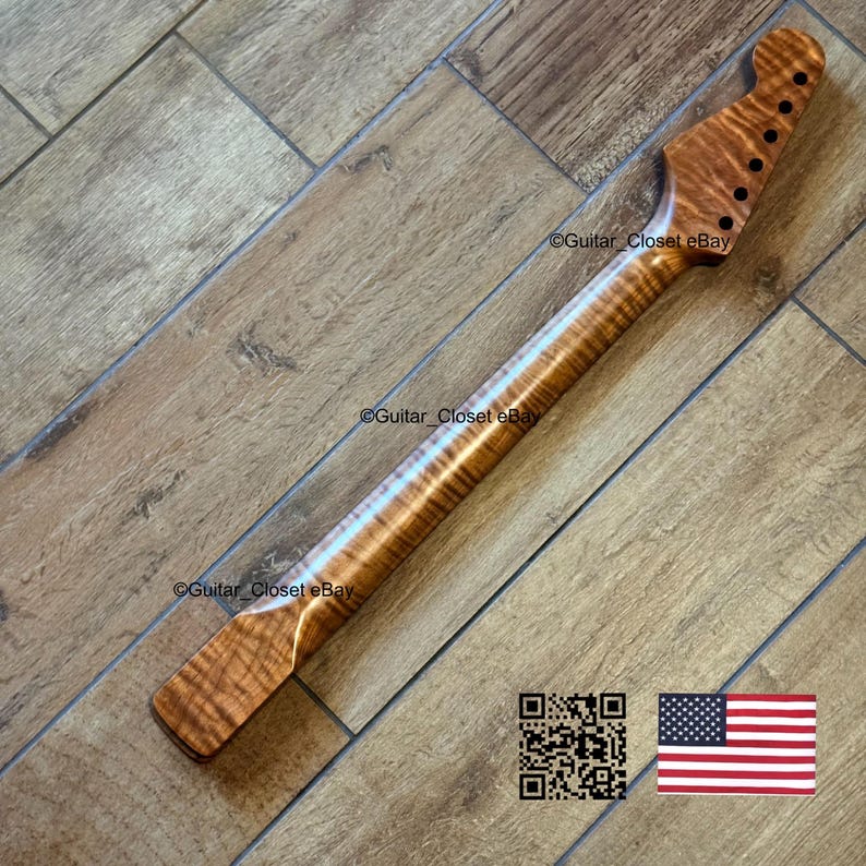 May include: A guitar neck crafted from figured maple, displaying a natural wood grain pattern in a light brown hue. The headstock features six tuning peg holes. The image also includes a QR code and the American flag.