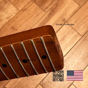 K&ouml;nnte beinhalten: Nahaufnahme eines Vintage-Gitarrenhalses mit B&uuml;nden und schwarzen Punkteinlagen. Das Holz hat einen warmen, r&ouml;tlich-braunen Farbton. Das Bild enth&auml;lt einen QR-Code und die amerikanische Flagge.