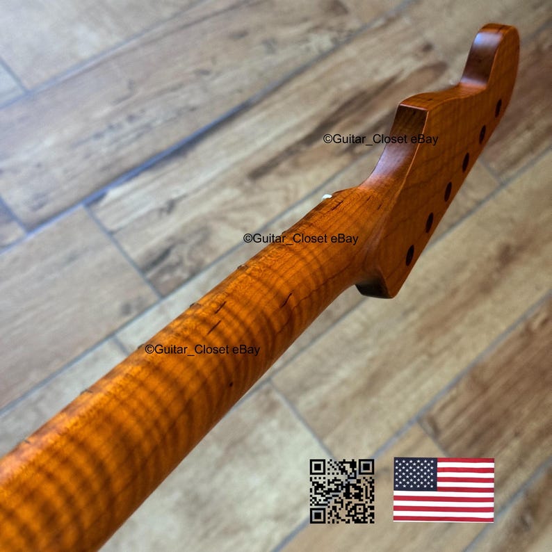Puede incluir: Primer plano de un m&aacute;stil de guitarra de madera de arce veteado, con un color &aacute;mbar c&aacute;lido y un patr&oacute;n de vetas onduladas prominente. El clavijero presenta orificios para las clavijas de afinaci&oacute;n. La imagen incluye un c&oacute;digo QR y la bandera estadounidense.