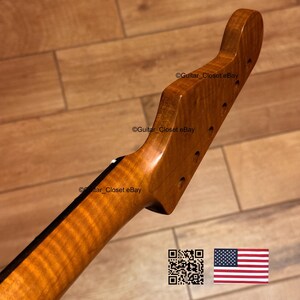 May include: A wooden guitar neck with a natural finish, featuring a curved headstock and pre-drilled holes for tuning pegs. The wood grain is visible, and the neck has a dark stripe on the back. The image includes a QR code and the American flag.
