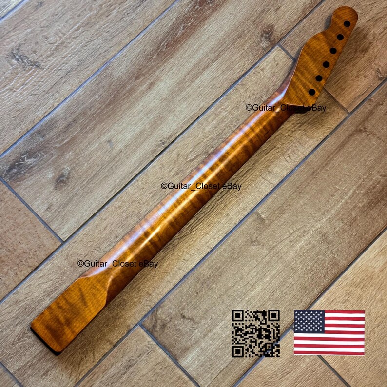 May include: A guitar neck made of figured maple wood, featuring a natural finish. The neck has a headstock with tuning peg holes and a fretboard area. The wood grain is visible. The image includes a QR code and an American flag.