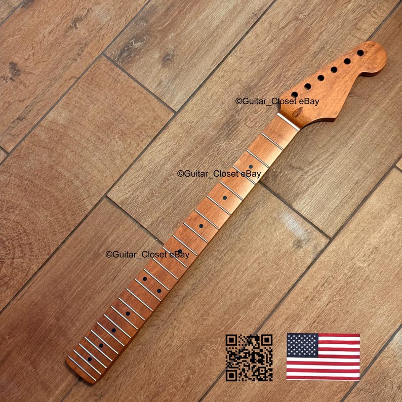 Pode incluir: Um bra&ccedil;o de guitarra novo, inacabado, feito de madeira clara. O bra&ccedil;o tem um cabe&ccedil;ote com orif&iacute;cios pr&eacute;-perfurados para as cravelhas e uma escala com marcadores de traste embutidos. A imagem inclui um c&oacute;digo QR e uma pequena bandeira americana.