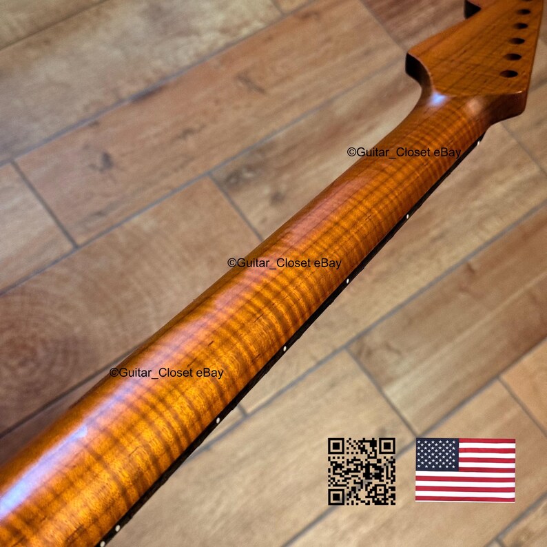 May include: Close-up of a guitar neck with a flamed maple finish. The wood grain has a wavy pattern with a warm, amber color. The headstock has tuning peg holes. The text "Guitar_ClosetEbay" is visible. An American flag and a QR code are in the image.