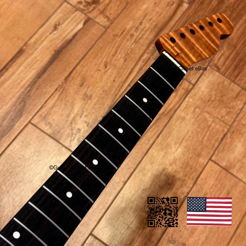 May include: A guitar neck featuring a dark brown fretboard with white circular position markers and silver frets. The headstock is made of light brown wood with a visible grain pattern and six pre-drilled holes for tuning pegs.