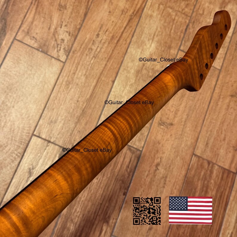 Puede incluir: Primer plano de un m&aacute;stil de guitarra de arce flameado. La veta de la madera presenta un patr&oacute;n de llama prominente, con un color &aacute;mbar c&aacute;lido. El clavijero tiene agujeros preperforados para las clavijas. El texto "Guitar_Closet eBay" es visible.