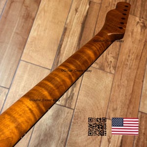 May include: A guitar neck with a flamed maple finish. The neck is a warm amber color with dark brown figuring. The headstock has pre-drilled holes for tuning pegs. The image includes a QR code and a small American flag.
