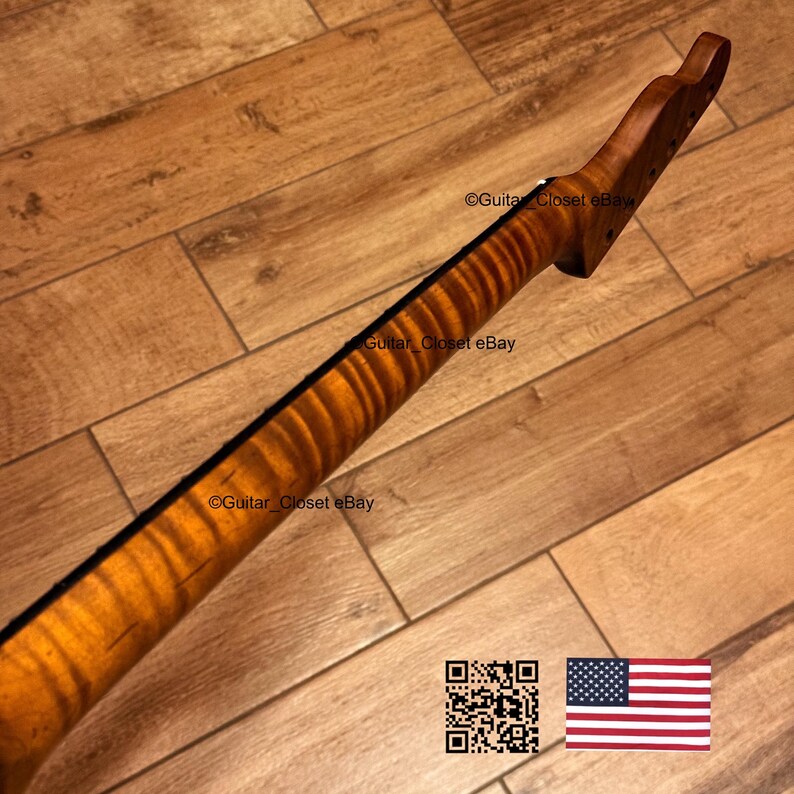 May include: A wooden guitar neck with a flamed maple grain pattern. The neck is a warm, amber color with a dark stripe down the center. The headstock has tuning peg holes. The text "Guitar Closet eBay" is visible.