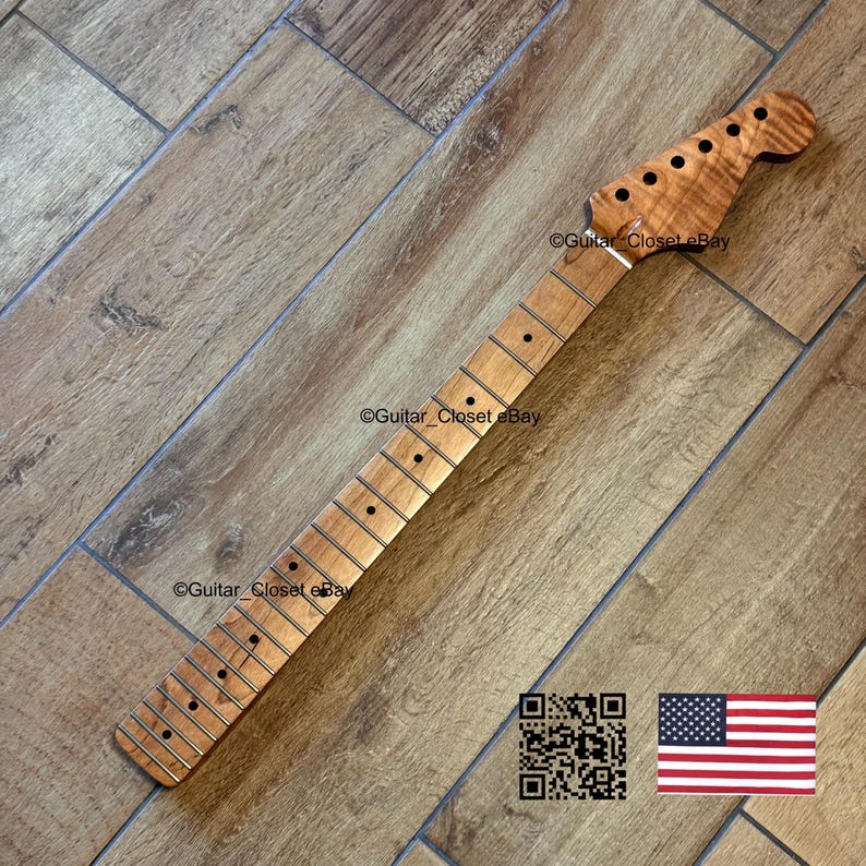 May include: A light brown guitar neck with a headstock featuring tuning peg holes. The neck has frets and dot inlays. The image includes a QR code and a small American flag.