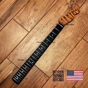 May include: A guitar neck featuring a dark ebony fretboard with white circular position markers and silver frets. The headstock is crafted from figured wood with a natural grain pattern and includes six pre-drilled holes for tuning pegs.