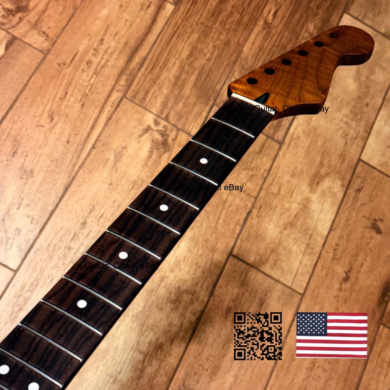 May include: A guitar neck featuring a dark brown wood fretboard with white circular position markers and silver frets. The headstock is made of a light brown wood with six circular holes for tuning pegs. A QR code and a US flag are visible.