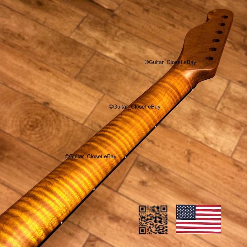 May include: A close-up of a guitar neck with a flamed maple finish. The neck is a warm amber color with a wavy grain pattern. The headstock has tuning peg holes. The text "Guitar_Closet eBay" is visible. An American flag is in the bottom right corner.