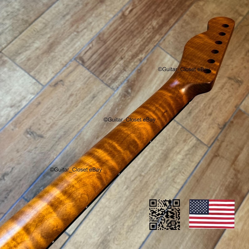 May include: A close-up of a guitar neck with a flamed maple finish. The neck is a warm, amber color with dark brown grain patterns. The headstock has tuning peg holes. The image includes a QR code and a small American flag.