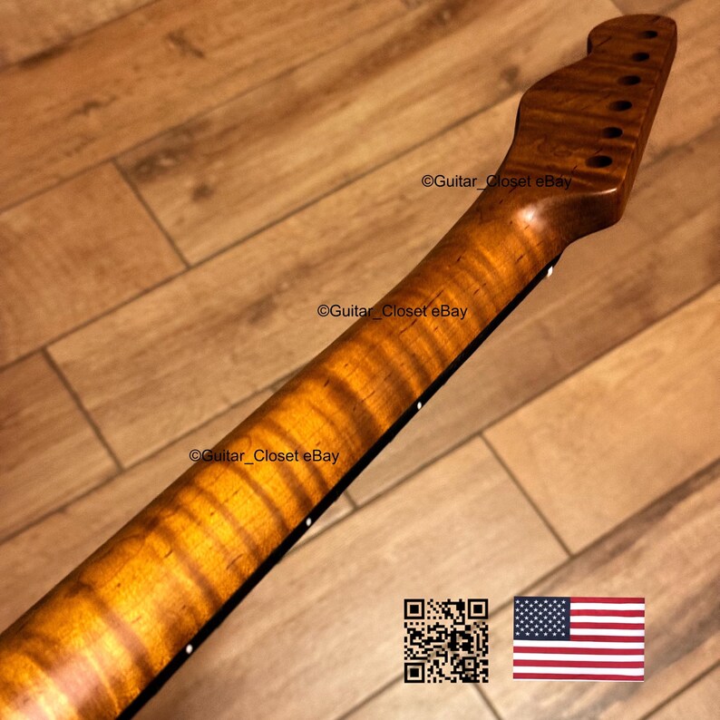 May include: A close-up of a guitar neck with a flamed maple finish. The neck is a warm, amber color with dark brown grain patterns. The headstock has tuning peg holes. The text "Guitar Closet eBay" is visible.