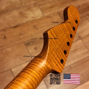 May include: A close-up of a guitar neck with a flamed maple finish. The headstock has six tuning peg holes. The wood grain is visible. The text "Guitar_Closet eBay" is visible. An American flag is in the bottom right corner.