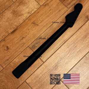 Peut inclure: Manche de guitare noir avec une t&ecirc;te, des trous de chevilles et une zone de touche. Le manche est pos&eacute; sur un fond en bois. L'image comprend un code QR et le drapeau am&eacute;ricain.