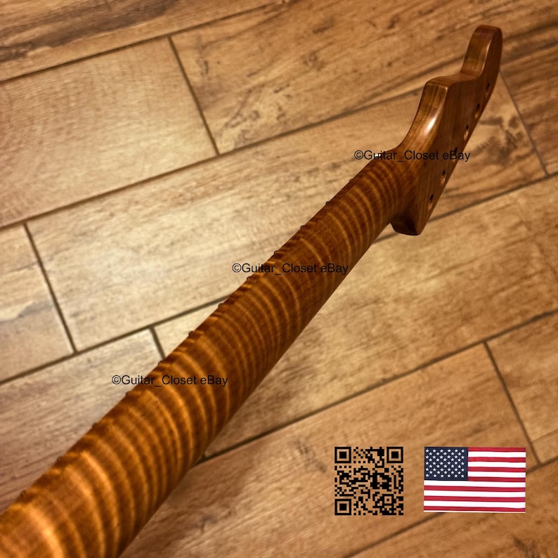 Puede incluir: Un m&aacute;stil de guitarra de madera marr&oacute;n claro con un patr&oacute;n de veta de arce flameado con rayas de tigre. El clavijero presenta varios orificios pretaladrados para las clavijas. El texto Guitar_Closet eBay es visible en la madera.