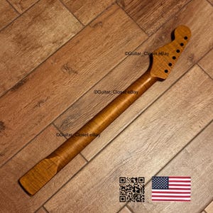 May include: A guitar neck crafted from light brown wood, featuring a flamed grain. The headstock has six tuning peg holes. The image includes a QR code and the American flag.