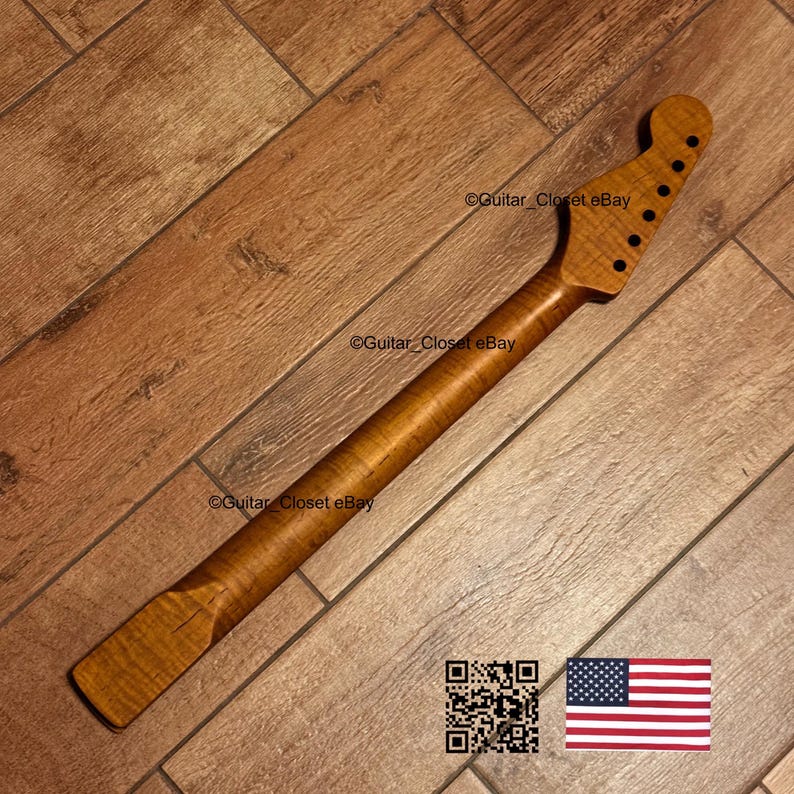 May include: A guitar neck crafted from light brown wood, featuring a flamed grain. The headstock has six tuning peg holes. The image includes a QR code and the American flag.
