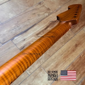 Puede incluir: Primer plano de un m&aacute;stil de guitarra de madera de arce veteado. La madera tiene un color &aacute;mbar c&aacute;lido con un patr&oacute;n de llama prominente. El clavijero presenta agujeros para las clavijas. La imagen incluye un c&oacute;digo QR y la bandera estadounidense.