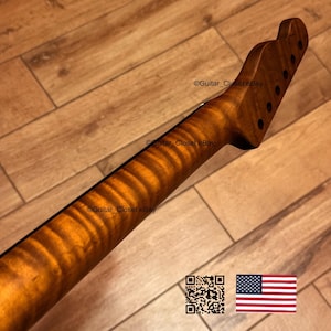 May include: A guitar neck with a flamed maple finish. The neck is a light brown color with a wavy grain pattern. The headstock has six tuning peg holes. The image also includes a QR code and an American flag.