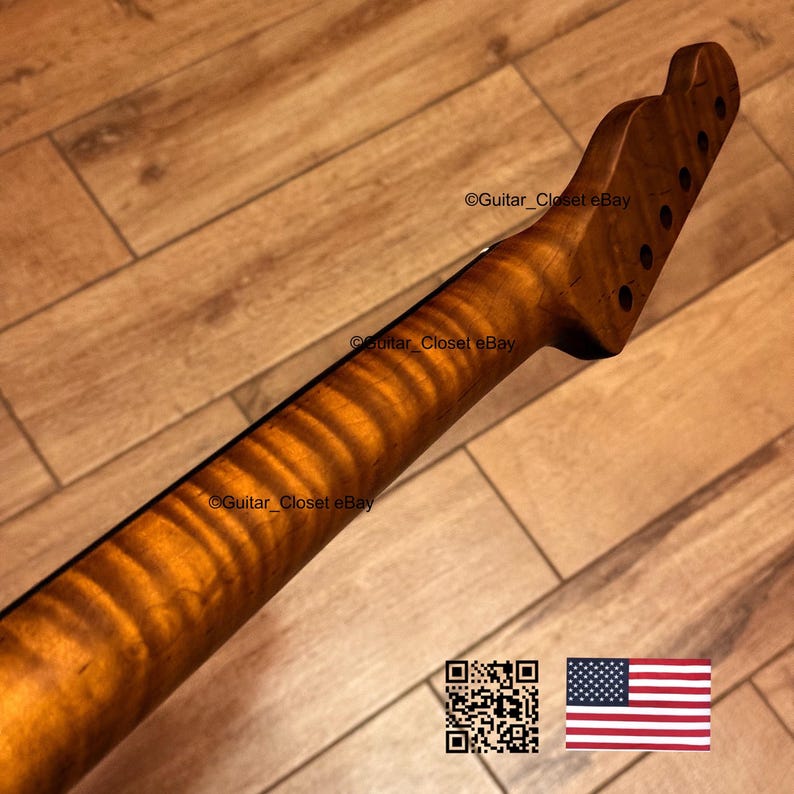 May include: A guitar neck with a flamed maple finish. The neck is a light brown color with a wavy grain pattern. The headstock has six tuning peg holes. The image also includes a QR code and an American flag.