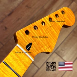 May include: Close-up of a guitar neck and headstock. The headstock is a light amber color with six tuning peg holes. The neck has a white stripe and black fret lines. The image includes the text "Guitar_Closet eBay".
