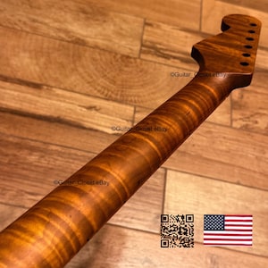 May include: A guitar neck made of brown wood with a prominent tiger-stripe flame maple grain pattern. The headstock features six tuner holes arranged in a row. The text Guitar_Closet eBay is visible on the neck and headstock, with a QR code and a US flag.