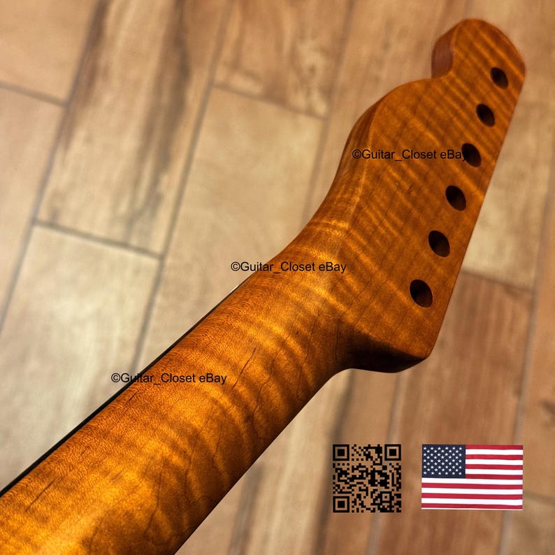 May include: A guitar neck with a flamed maple finish. The wood grain has a wavy pattern with a golden-brown color. The headstock has six tuning peg holes. The image includes a QR code and the American flag.