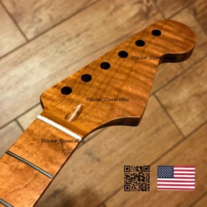 Puede incluir: Un m&aacute;stil de guitarra con pala de arce flameado marr&oacute;n claro, seis orificios para clavijas, acabado en madera lisa y cejuela blanca. El texto Guitar_Closet eBay es visible. Se incluyen un c&oacute;digo QR y una peque&ntilde;a bandera de los Estados Unidos.