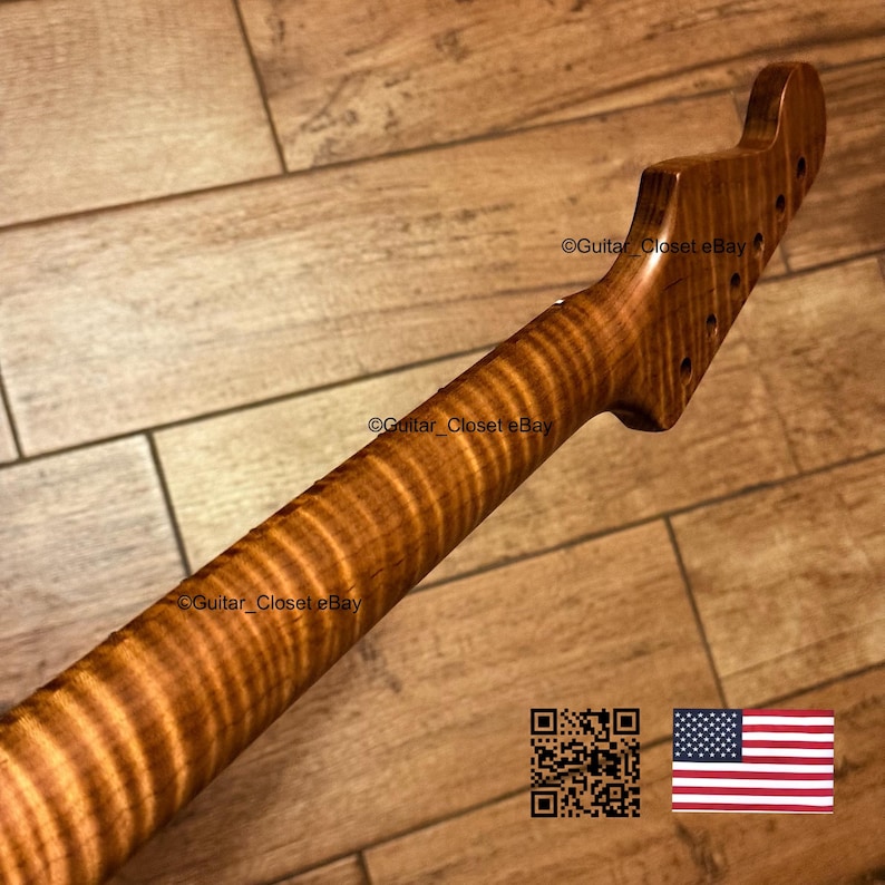 Puede incluir: Un m&aacute;stil de guitarra hecho de madera marr&oacute;n claro con un patr&oacute;n de veta de arce flameado con rayas de tigre. El clavijero presenta seis orificios pretaladrados para las clavijas. La superficie tiene un acabado liso y pulido con texturas naturales.
