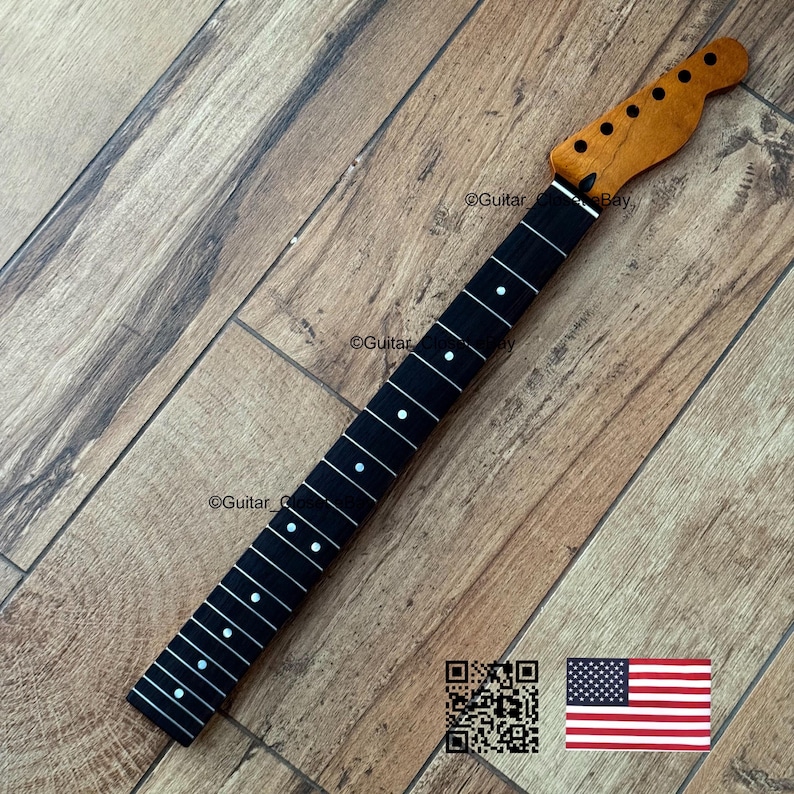 以下が含まれることがあります： 自然な木材仕上げのヘッドストックと、白いドットインレイが付いた黒い指板を備えたギターネック。 ネックは木製の表面に角度が付けられています。 画像にはQRコードと小さなアメリカ国旗が含まれています。