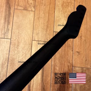 May include: A black guitar neck with a headstock, possibly for an electric guitar. The wooden neck has a smooth, dark finish. The image includes a QR code and the American flag.