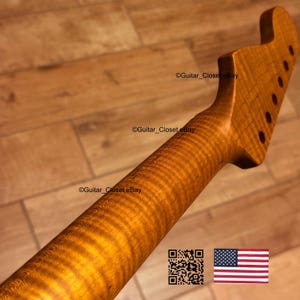 May include: A guitar neck crafted from figured maple, displaying a natural wood grain. The headstock has six tuning peg holes. The text "Guitar_Closet eBay" is visible. An American flag is in the bottom right corner.